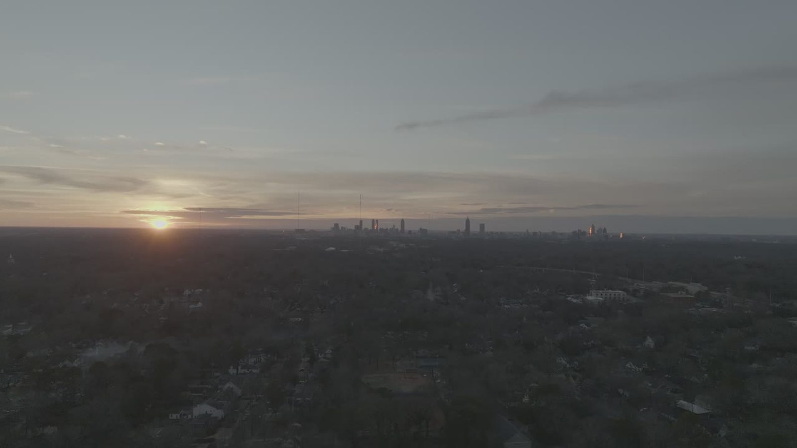 Sun low over the Atlanta horizon with warm light across the treeline